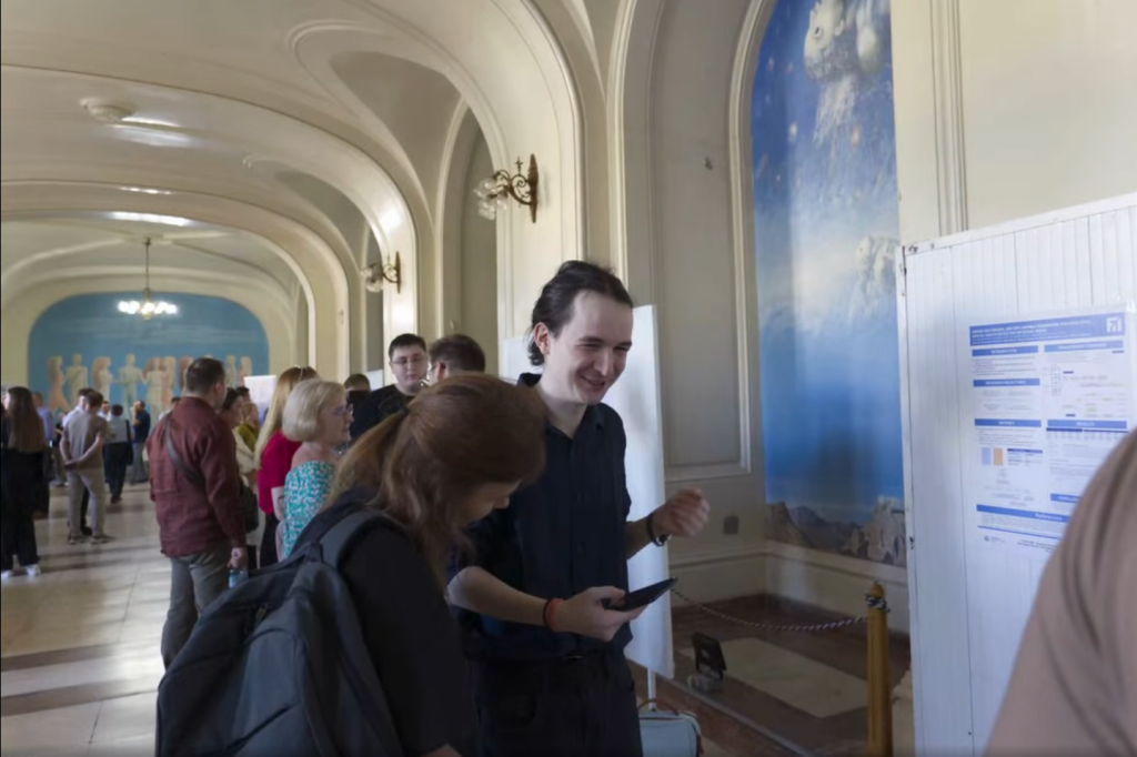 Cercetător prezentând un poster științific într-o sală a universității