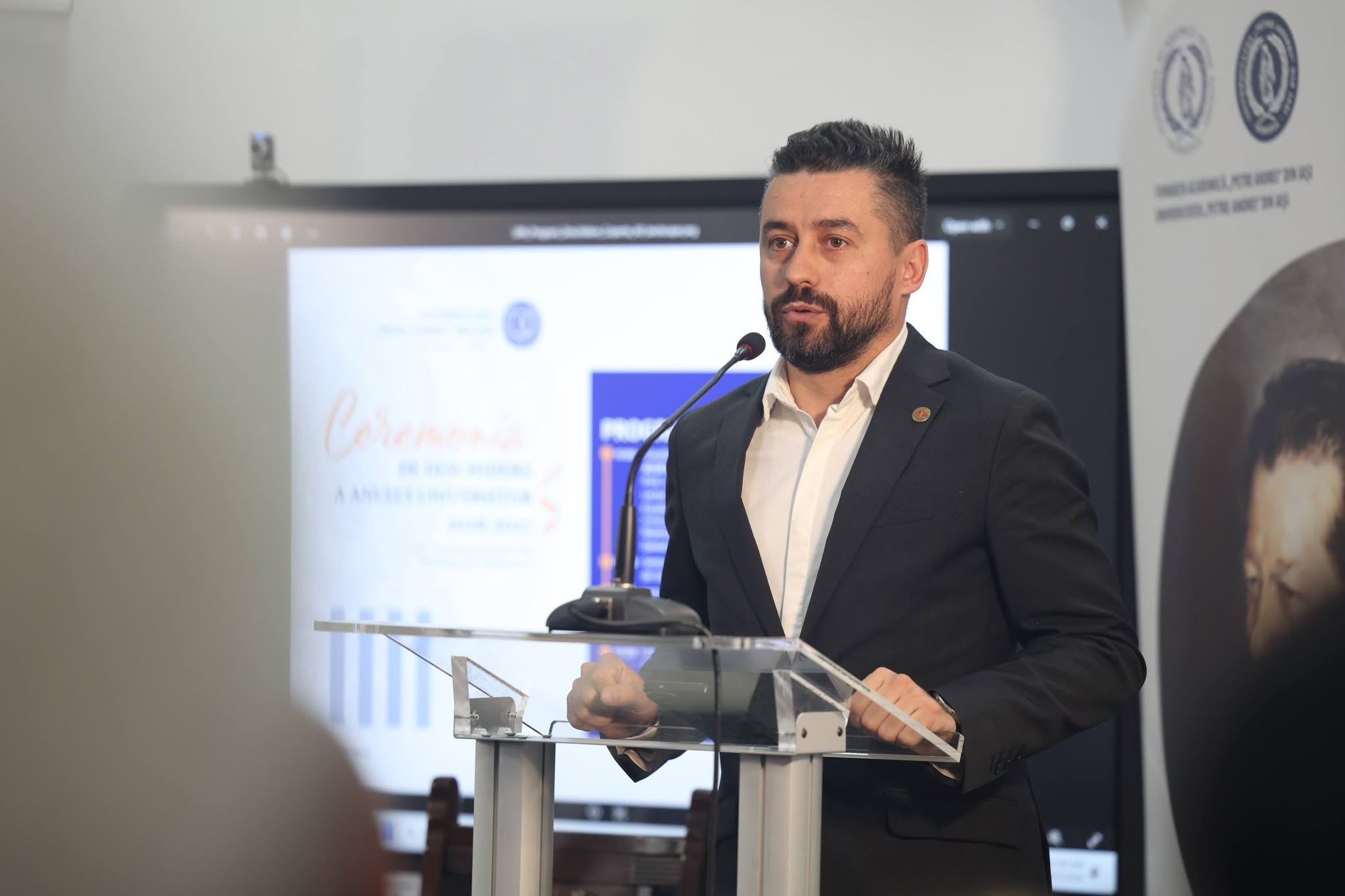 Alexandru Calance vorbind la un pupitru, într-o sală de conferințe