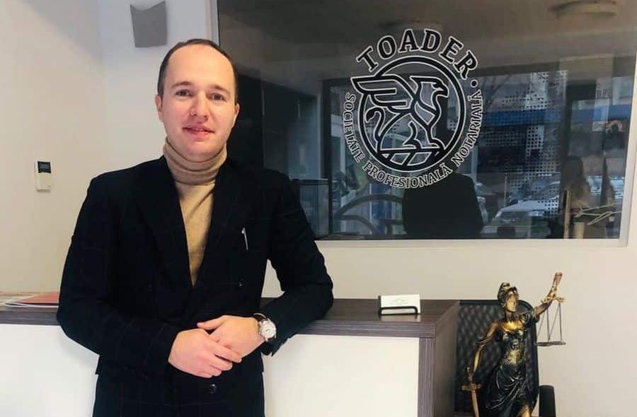 Alexandru Toader în biroul notarial din Iași, cu sigla cabinetului pe peretele de sticlă