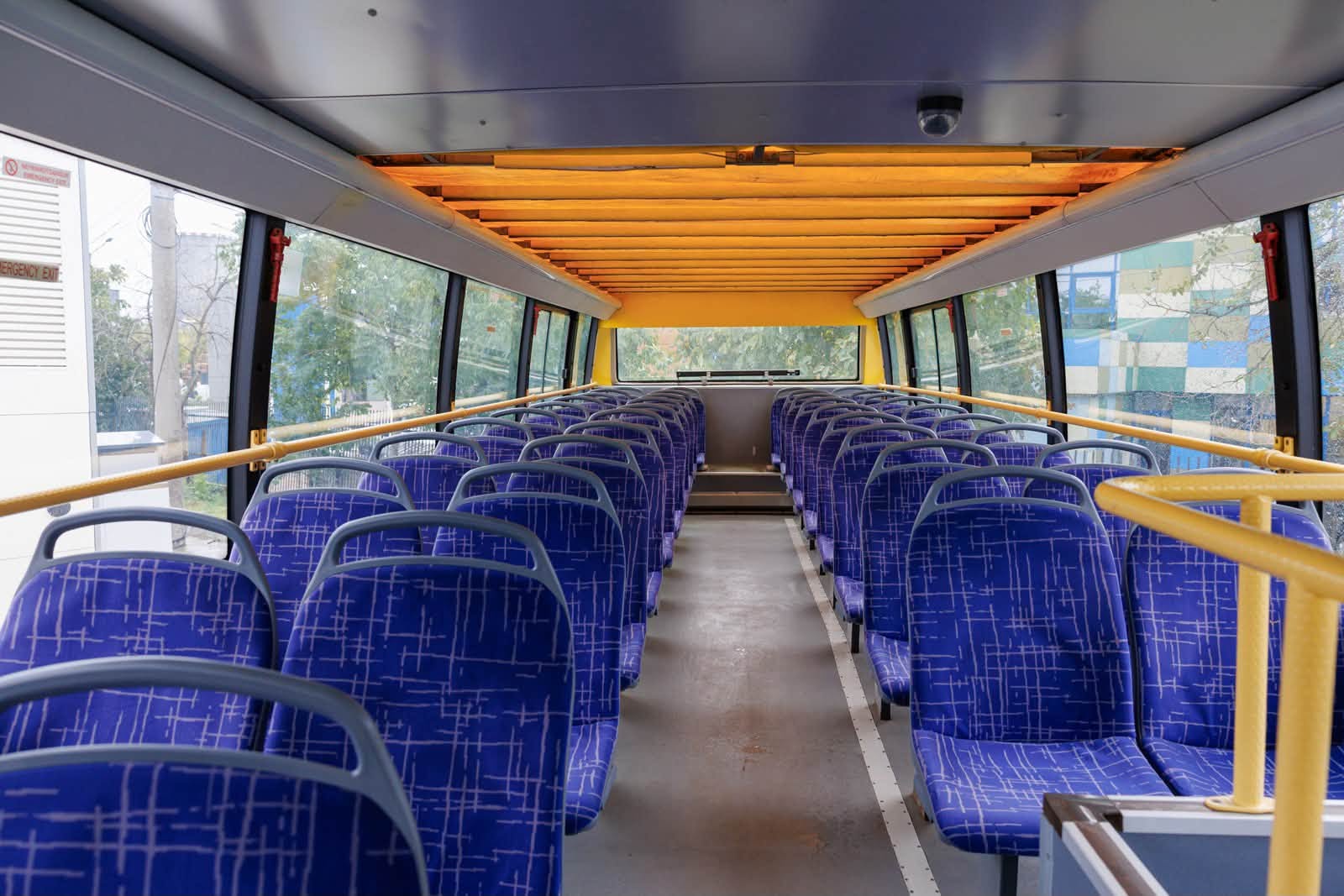 Etajul superior al autobuzului turistic, cu scaune albastre si copertina