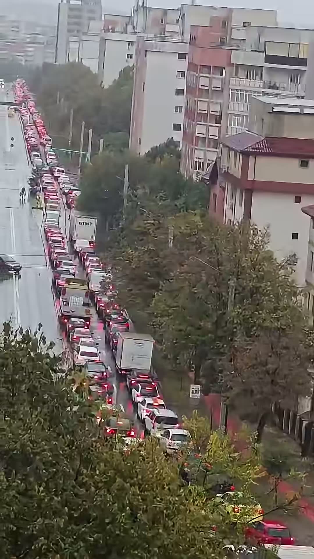 Șir de mașini oprite pe o stradă îngustă dintre blocuri, în Iași