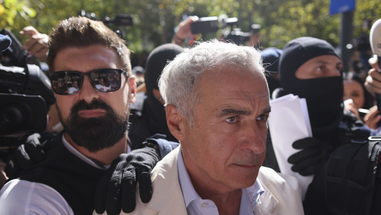 Călin Georgescu, escortat de oameni ai forțelor de ordine în mijlocul unei mulțimi de jurnaliști