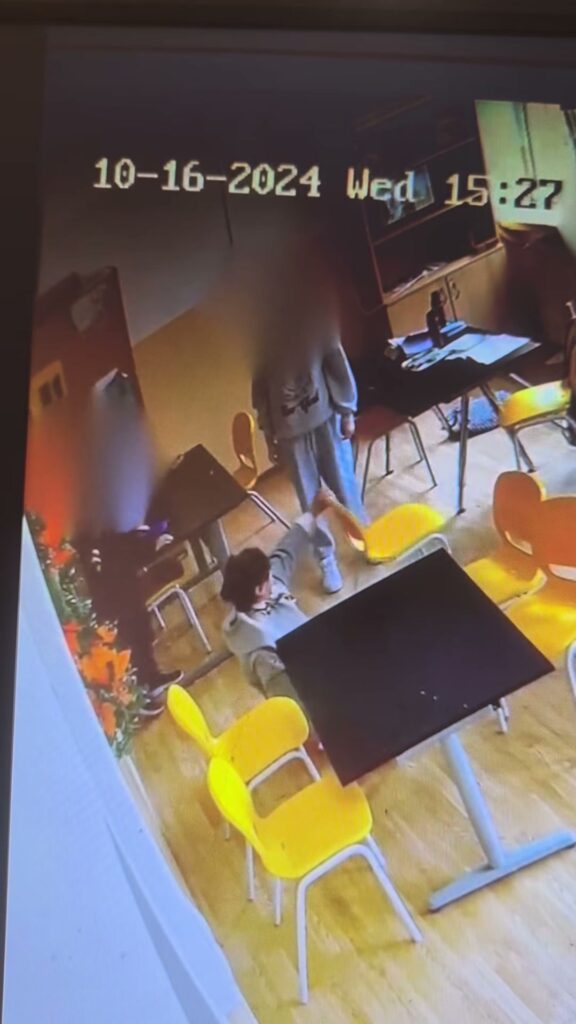 Captură din filmare: persoană căzută la podea, lângă mese, cu ceasul camerei la 15:27
