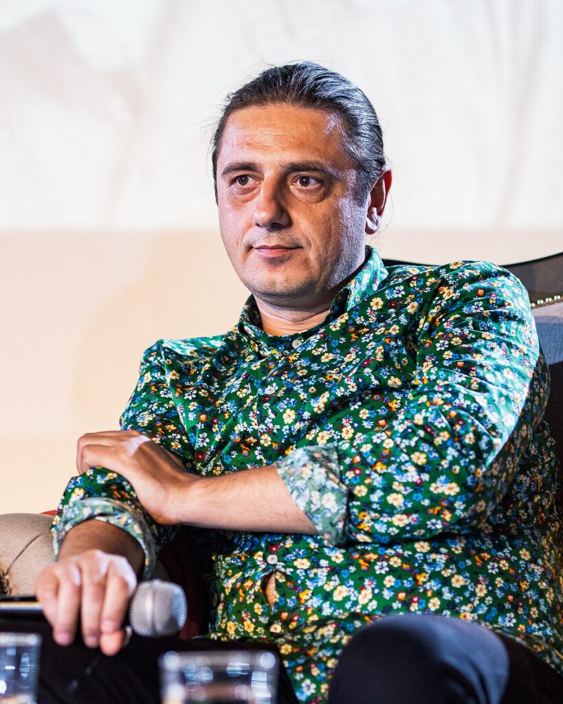 Scriitorul Florin Lăzărescu, așezat, într-o cămașă cu flori