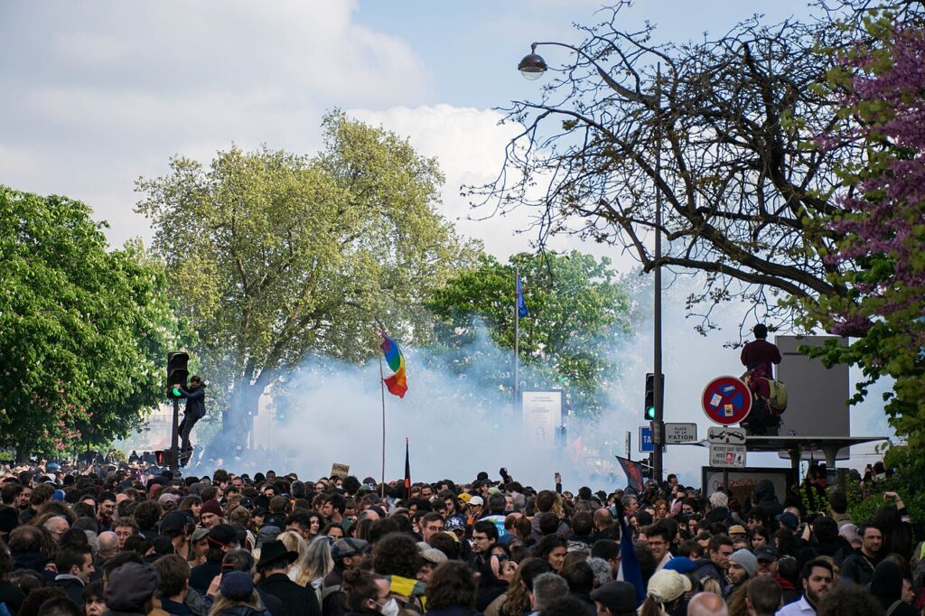 Mulțime de manifestanți și nori de gaze lacrimogene pe un bulevard din Paris