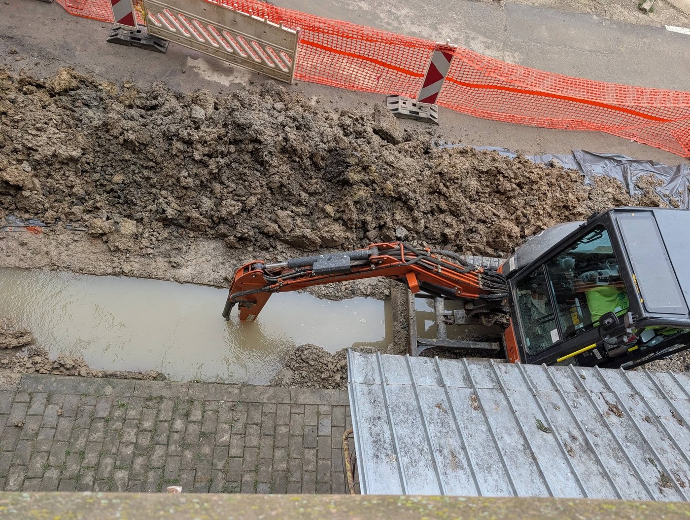 Miniexcavator oprit într-un șanț plin cu apă, lângă un bloc din Păcurari