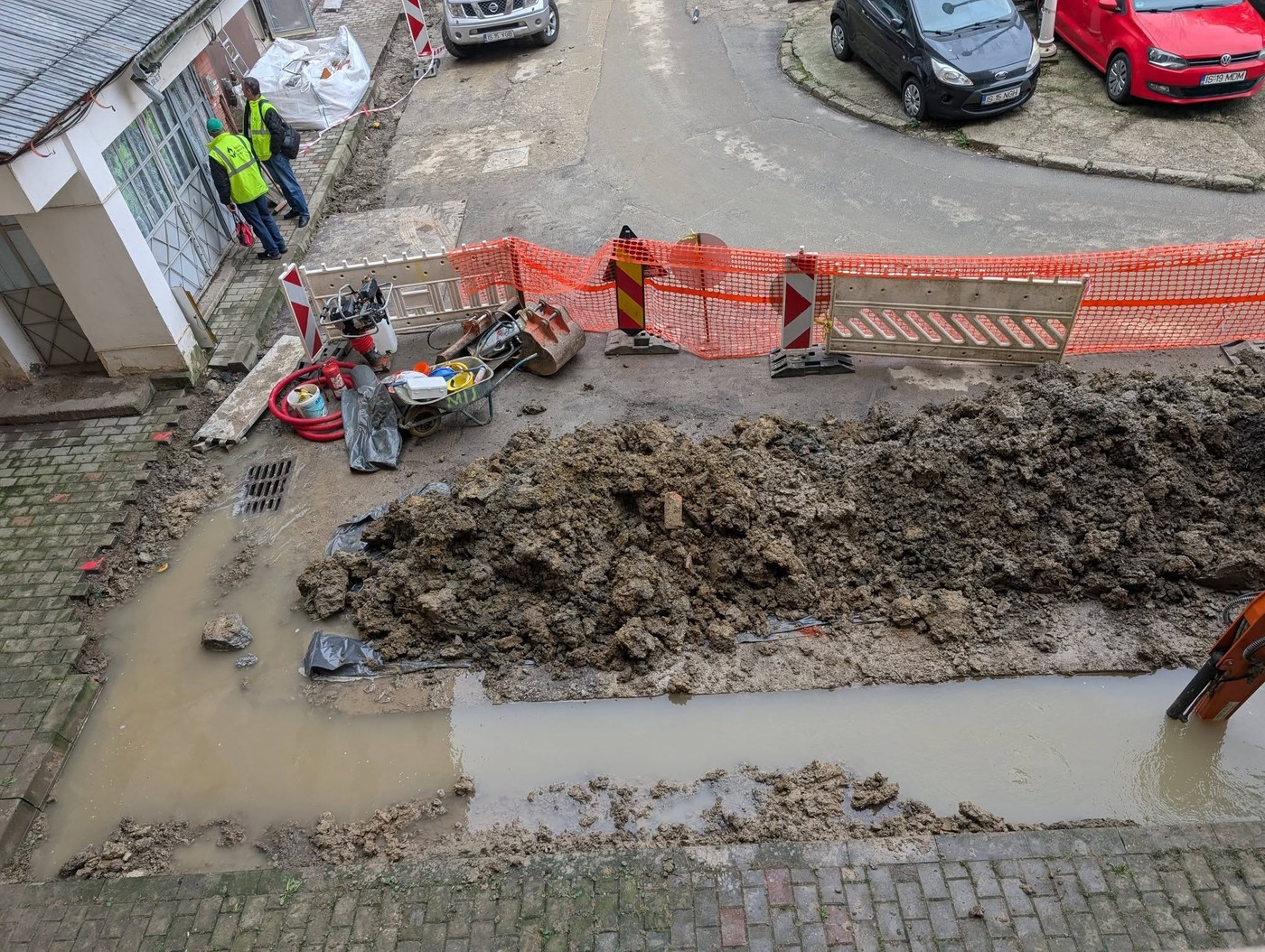 Șanț săpat în spatele unui bloc din Păcurari, plin cu apă și pământ, împrejmuit cu plasă portocalie