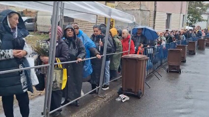 Pelerini cu umbrele și haine de ploaie, la rând între garduri metalice, pe culoarul spre Catedrala Mitropolitană
