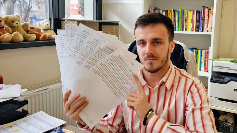 Petruț Rizea ținând în mână fișe de lucru, într-o sală de clasă