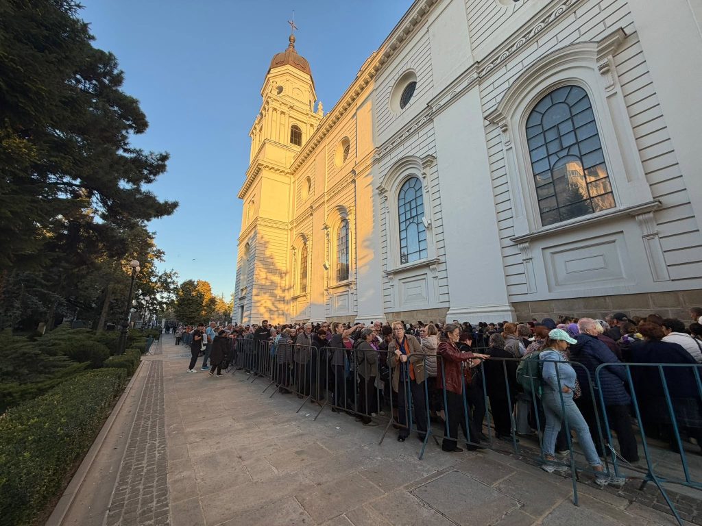 Șir lung de pelerini la gardurile de-a lungul Catedralei Mitropolitane din Iași, în lumina dimineții